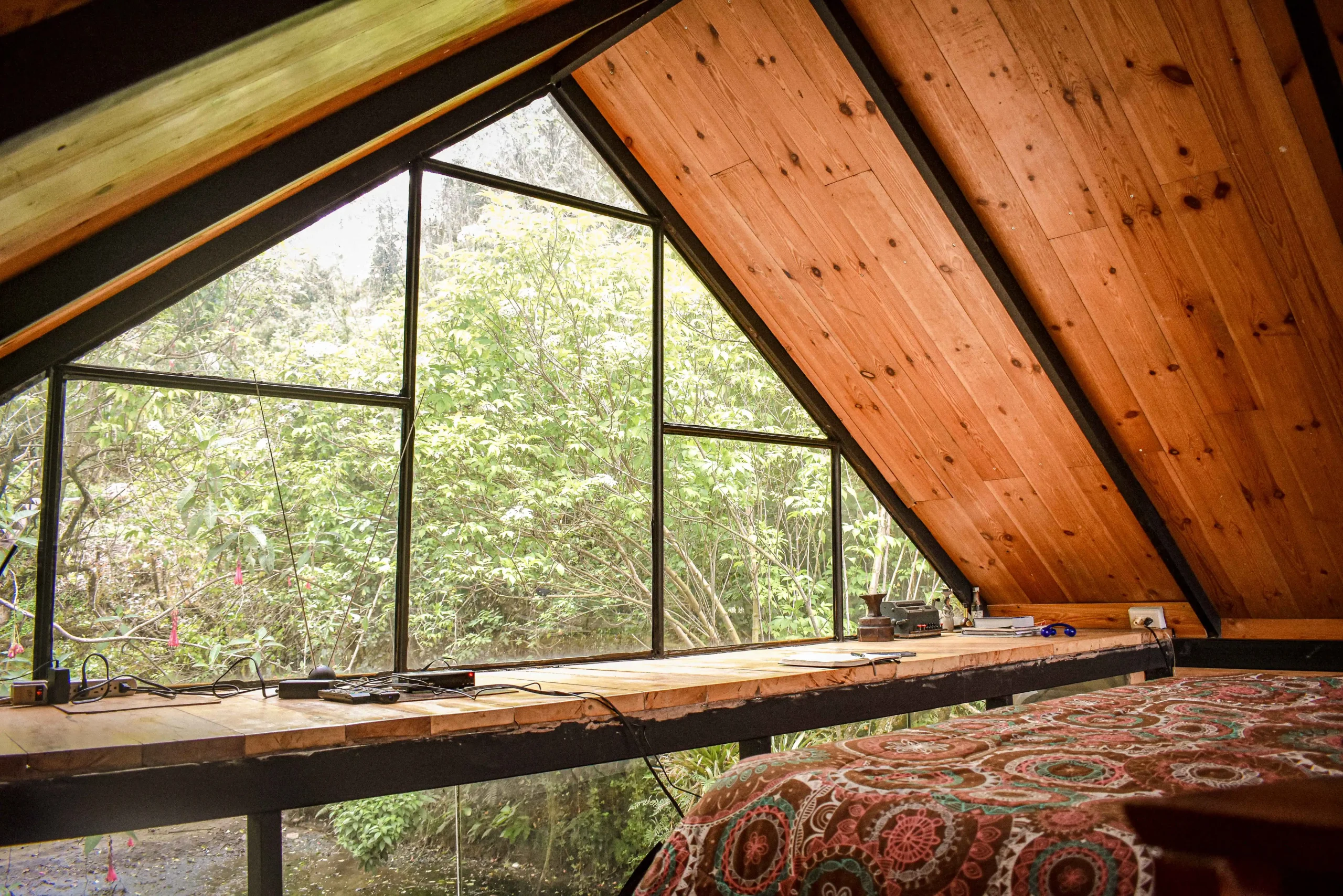 Coin chambre aménagé sous les combles avec vue sur la nature, bois apparent et lumière naturelle. Architecture d’intérieur Marseille